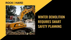 Excavator demolishing structure during winter with snow on ground